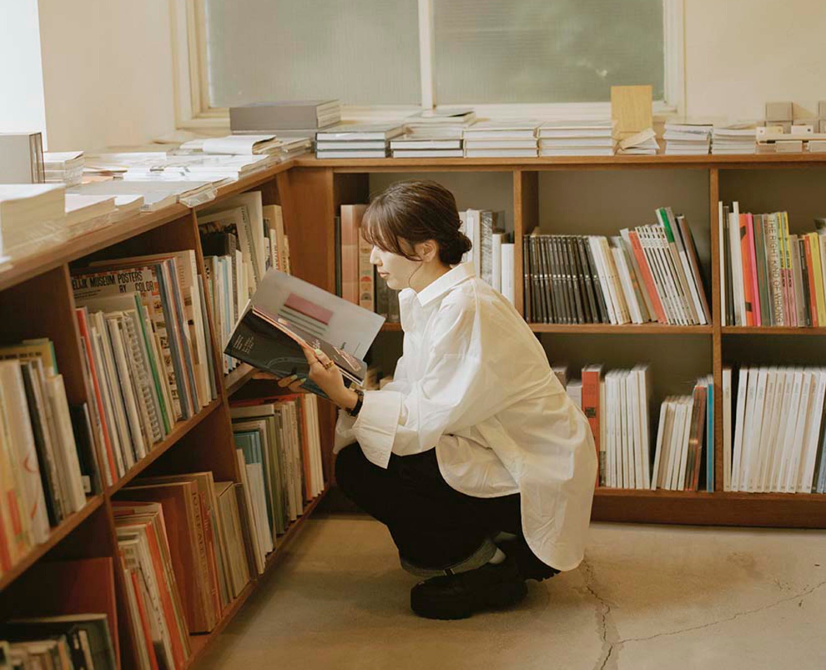 三宅香帆さんが書棚で本を読む様子